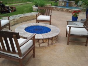 stone patio and waterfall with fire pit & wooden chairs