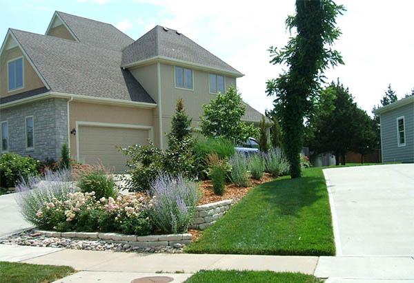 New landscaping with flowers, bushes, trees, grass, stones, and more