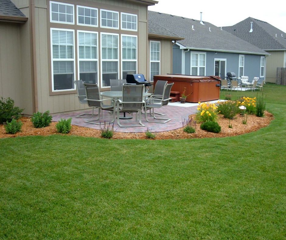 landscaped patio with outdoor table grill and hot tub